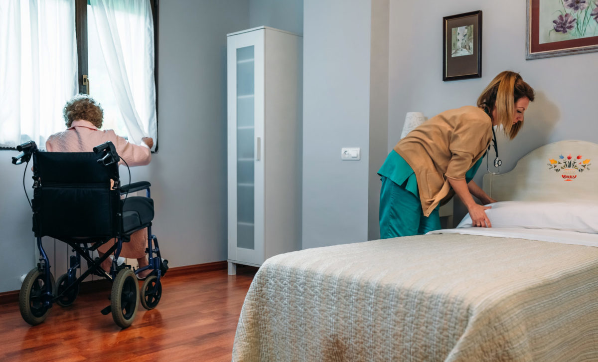 Caregiver making the bed of an elderly patient