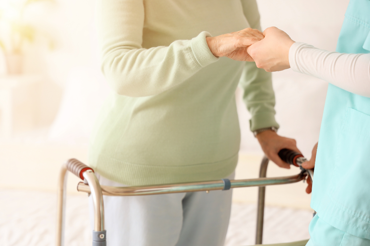 A person holding a walker talks with another person.